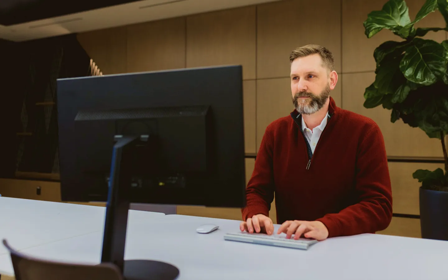 Man typing on keyboard looking at large monitor