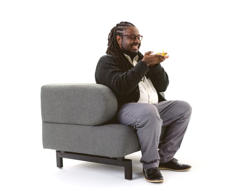 Happy man smiling and sitting in a chair while holding an origami crane