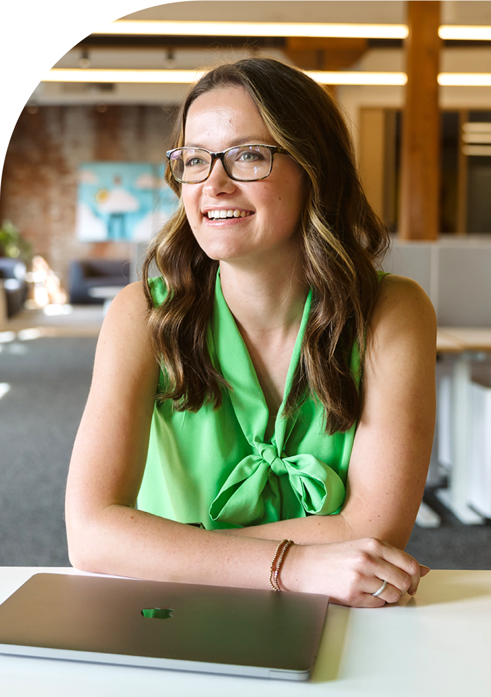 woman with glasses in green blouse sitting behind a closed laptop talking about WordPress Hosting