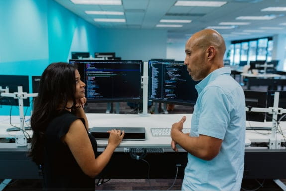 Man and woman talking in front of computer desk